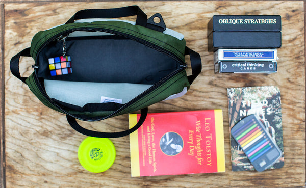 A Silver sided Grab Bag with various card games, and other items next to it.